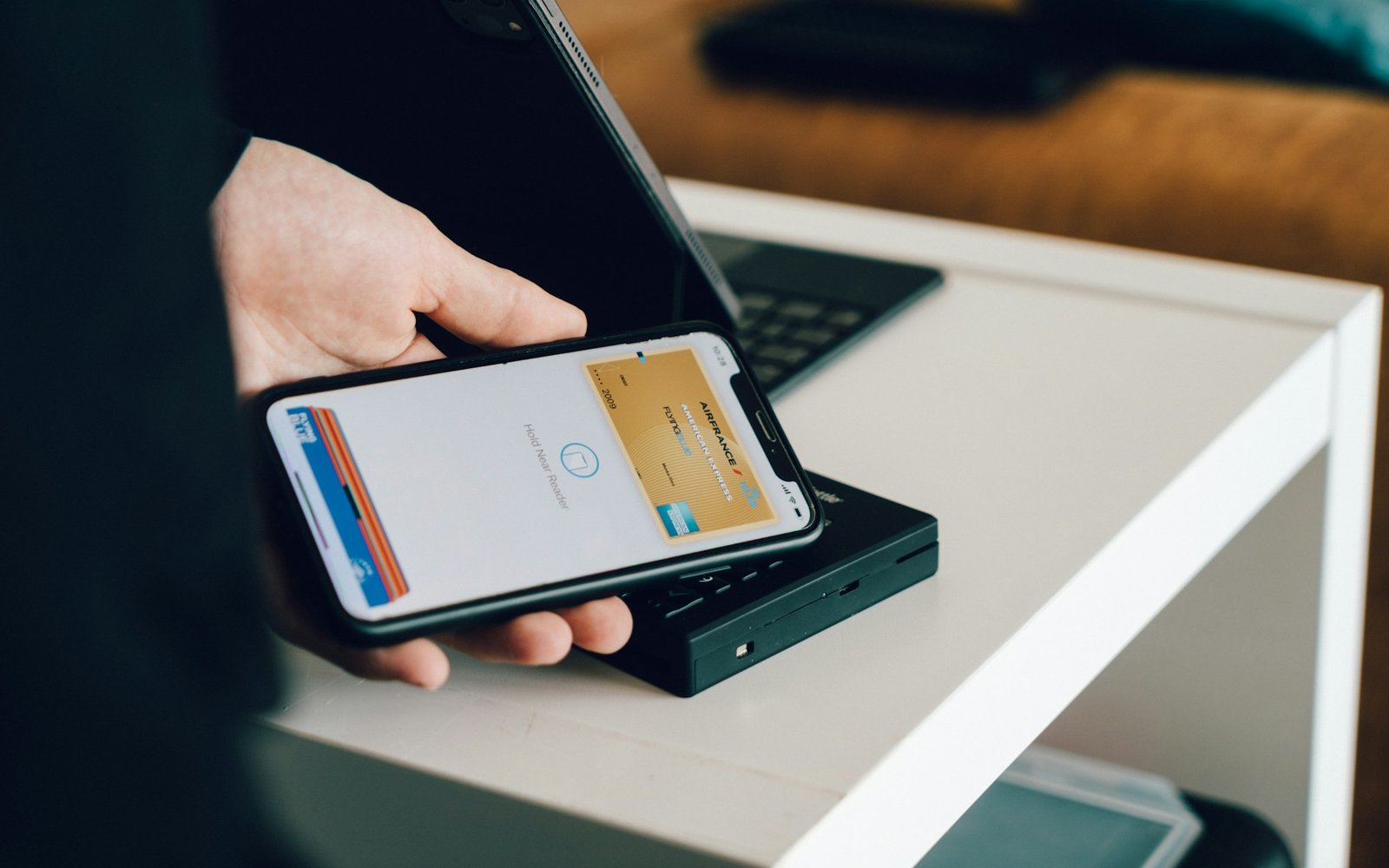 Person holding a smartphone over a card reader for contactless payment