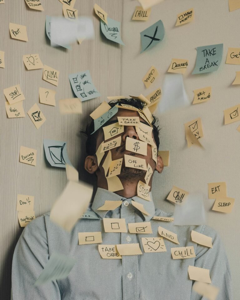Man covered in sticky notes at office desk representing financial overwhelm