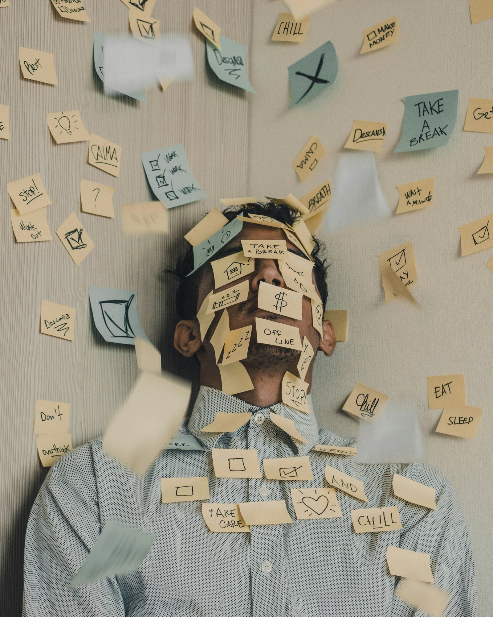 Man covered in sticky notes at office desk representing financial overwhelm