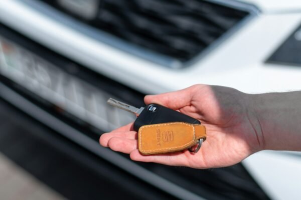 Person holding a car key at a dealership representing first car purchase
