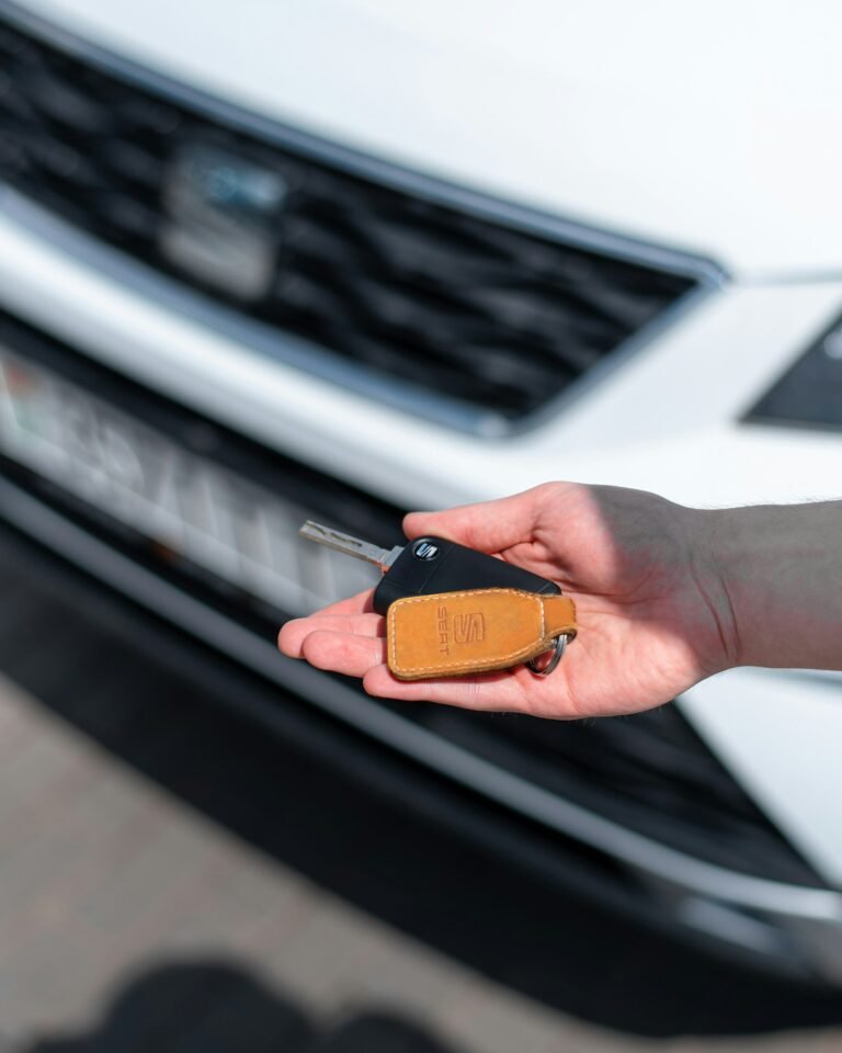 Person holding a car key at a dealership representing first car purchase